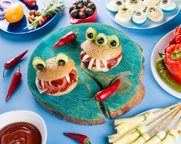Halloween party food. Stuffed peppers with scary faces, cheese witches brooms, monster hamburgers, witch finger treats.