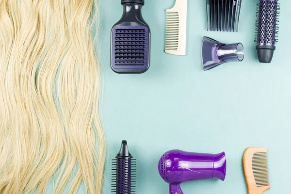 Hairdressing tools and hair extensions on blue wooden background. Top view, flat lay