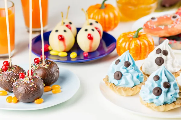 Halloween sweet treats, party food concept. White and blue cakes with faces close up. Top view