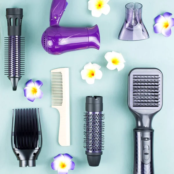 Hairdressing tools with flowers on blue wooden background. Top view, flat lay