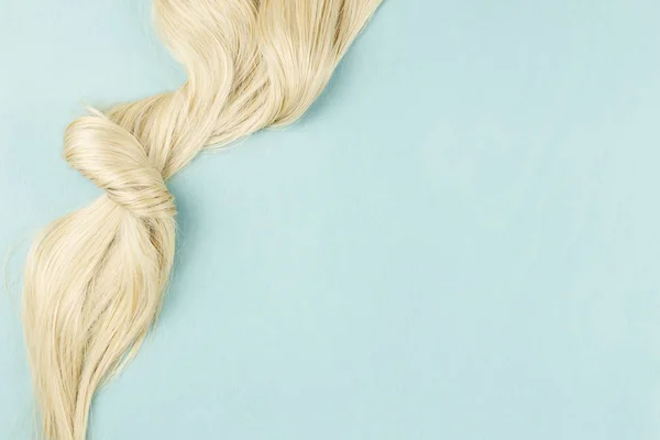 Hair extensions on blue wooden background.