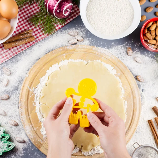 Christmas cookie ingredients, rolling pin, dough. Christmas cooking concept. Woman hands holding cookie cutter