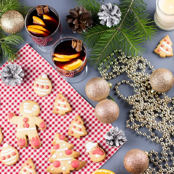 Tasty Christmas cookies, gift boxes and decorations with Christmas tree and lights on black background. Top view