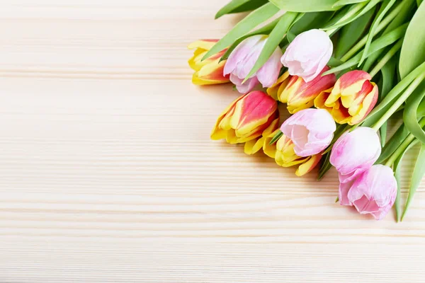Red and pink tulips on wooden background closeup, copy space