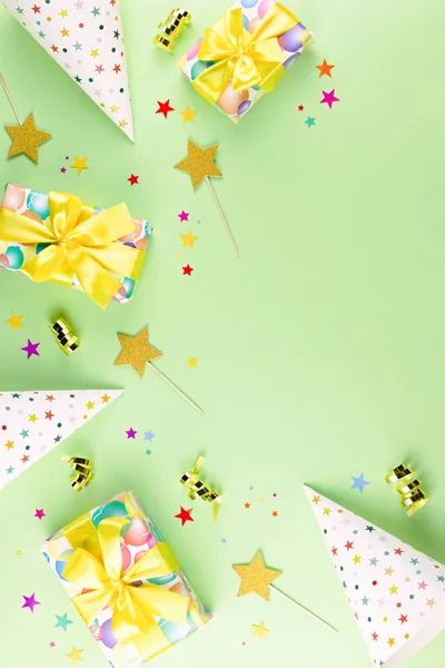 Birthday party background with wrapped gifts, confetti, party hats, decorations, top view
