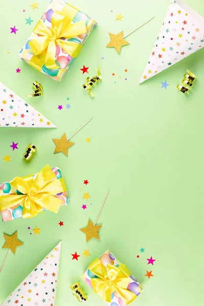 Birthday party background with wrapped gifts, confetti, party hats, decorations, top view