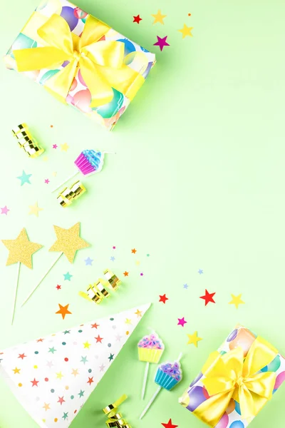 Birthday party background with wrapped gifts, confetti, party hats, decorations, top view