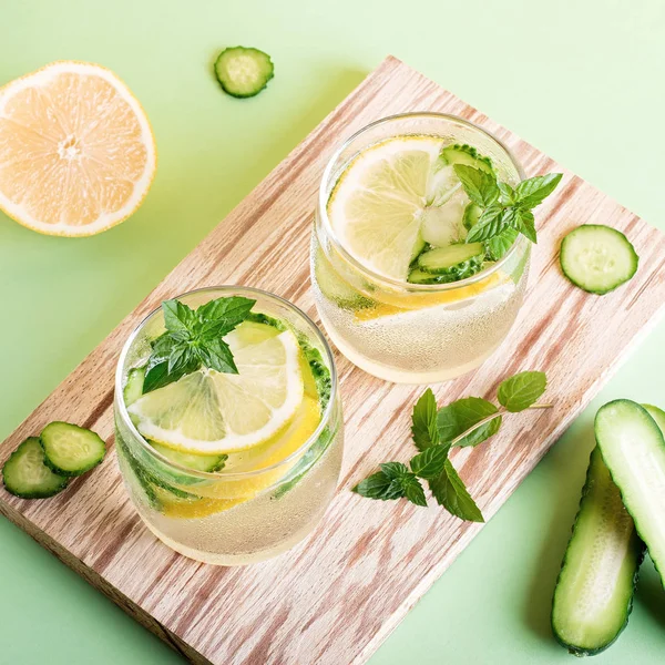 Summer refreshing non alcoholic cocktails with lemon, cucumber and mint, closeup on yellow background