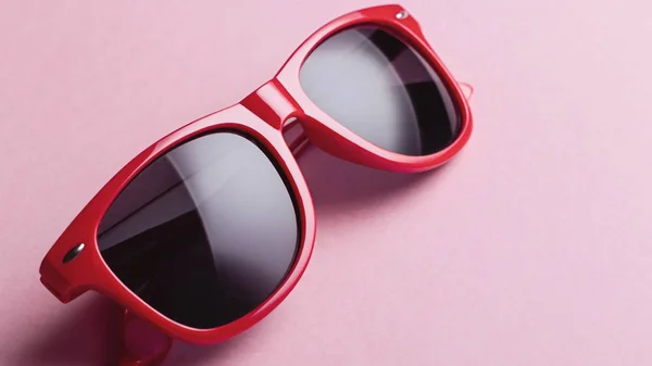 Stylish red sunglasses closeup on pink background, flat lay. Wayfarer shape sunglasses