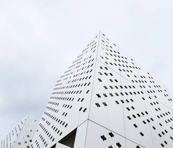 Modern buildings of unusual forms from white perforated metal.