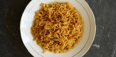 Stok fotoğrafı. Lezzetli kızarmış şehriye. Beyaz tabakta ve taş bir tabakta.