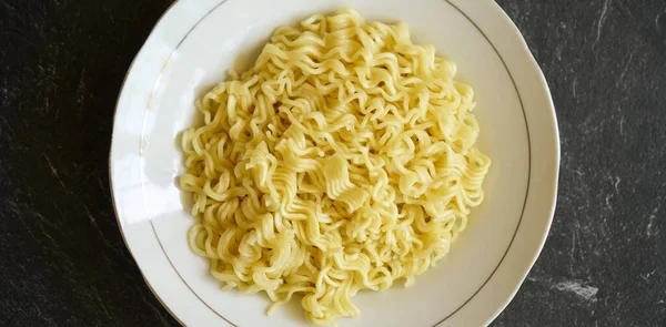 Foto Stock Sabroso Fideos Amarillos Plato Blanco Una Almohadilla Piedra —  Fotos de Stock