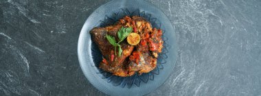 Kırmızı biberli ev yapımı papağan balığı, taş bir tabakta servis edilen Asya mutfağındaki yemektir.