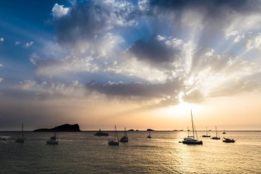 Gökyüzü bulutlar yoluyla ve denizin bir gün batımı sırasında patlama, güçlü renkler ve gölgeler döküm küçük adalar ve tekneler üzerinde güneş ışınlarının
