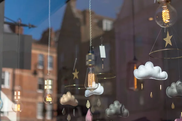 Decorative lights and fabric clouds hanging inside store on display viewd from the street with the city reflecting on the  glass