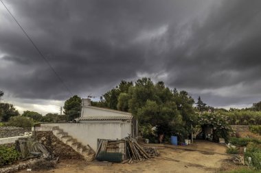 Biraz yeşillik ve merkezinde odun yığını menorca içinde ev grubu araçlar ve aydınlık toprak ekili olmak için çok küçük bir ev ile çevrili.