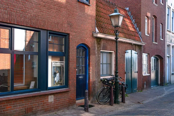 Vlissingen, Niederlande - April 2015: malerischer Blick auf eine Straße mit roten Backsteinhäusern, einer alten Straßenlaterne und zwei davor geparkten Fahrrädern. — Stockfoto