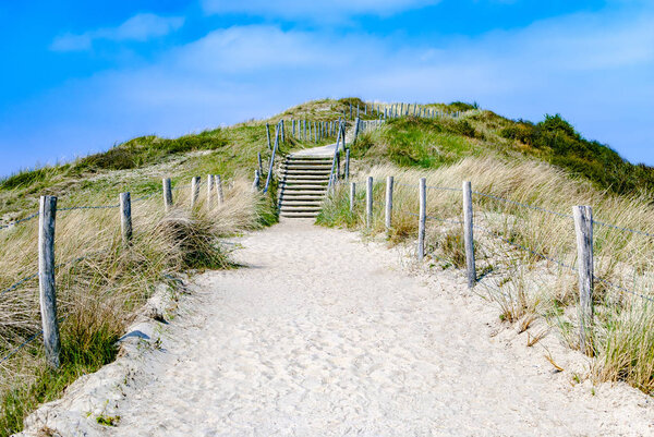 Empty sandy path with stairs through dunes leading to the beach. Summer. Vacation. The Netherlands. Travel. Path to unknown. Journey. Adventure. Destination.