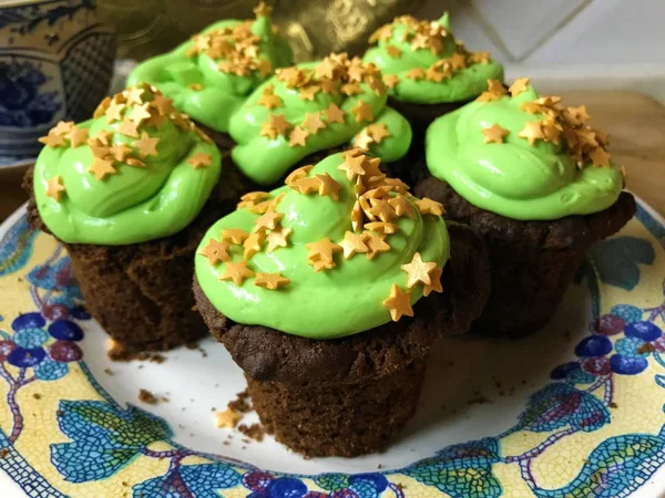 Cupcakes with green frosting and golden stars sprinkles on a white plate — Stock Photo, Image