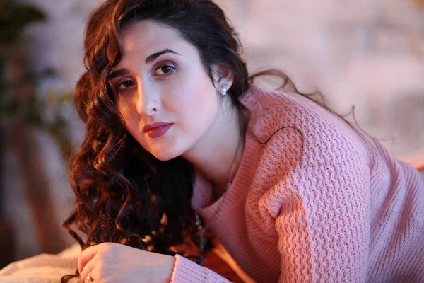 Rahat esmer, siyah saçlı kız yatağa uzanıyor.