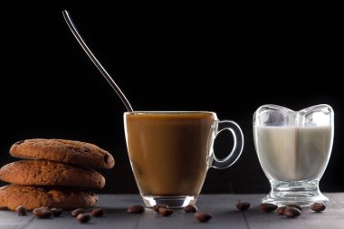 siyah bir arka plan üzerinde süt ve kurabiye ile kahve fincan