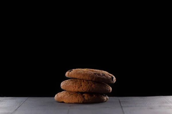 黒い背景に3つのオートミールクッキー — ストック写真