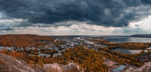 Black clouds over the city. Panoramic view from the mountains to the orange autumn landscape of the city, forests and rivers with islands. Red clay, the Volga river in the city of Samara.