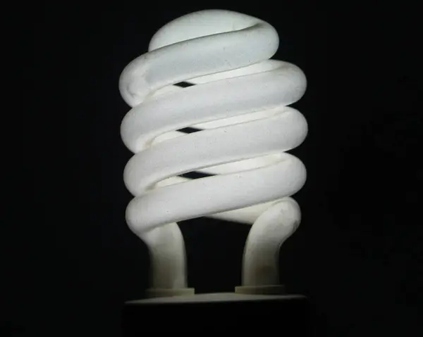 Una lampadina bianca a risparmio energetico e sfondo oscurato . — Foto Stock