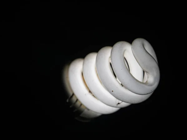 A white energy saving bulb and blacked background. — Stock Photo, Image