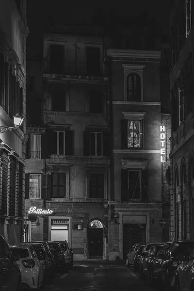 A narrow street and hotel sign at night in Rome, Italy