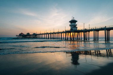 Gün batımı yansımaları ve Huntington Beach, turuncu Coun İskelesi