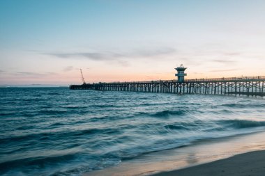 Pasifik Okyanusu'ndaki dalgalar ve Seal Beach, Orange Co'daki iskele