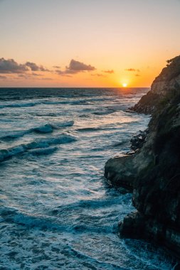 Swami Plajı'nda kayalık kıyıve Pasifik Okyanusu üzerinde gün batımı, 