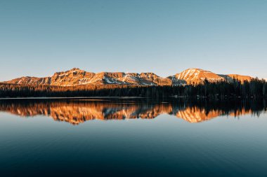 Snowy mountains reflecting in Mirror Lake, in the Uinta Mountain clipart