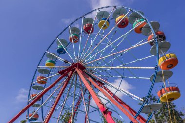 Tanımlanamayan bir lunapark içinde işgal edilmemiş dev dönme dolabı, çocuklar ve yetişkinler tatil sırasında eğlenceli yolculuk alarak zevk