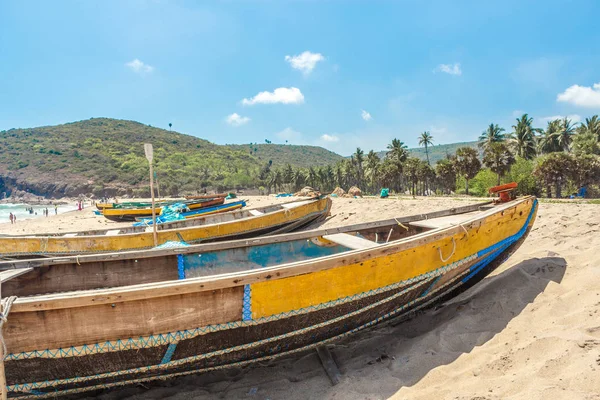 Narrow view of group of fishing boats parked alone in seashore and cliff in the background, Visakhapatnam, Andhra Pradesh