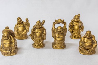 Gülen Buddha grubu beyaz bir zemin içinde altın renkte boyanmış. Son derece sığ alan derinliği ile makro konularda seçici odak.