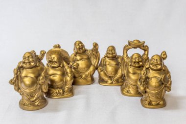 Gülen Buddha grubu beyaz bir zemin içinde altın renkte boyanmış. Son derece sığ alan derinliği ile makro konularda seçici odak.