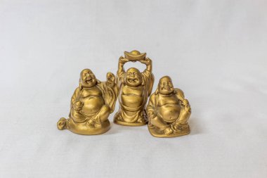 Gülen Buddha grubu beyaz bir zemin içinde altın renkte boyanmış. Son derece sığ alan derinliği ile makro konularda seçici odak.