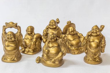 Gülen Buddha grubu beyaz bir zemin içinde altın renkte boyanmış. Son derece sığ alan derinliği ile makro konularda seçici odak.