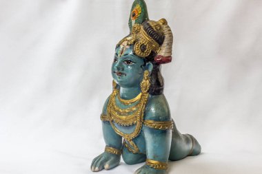 Beyaz bir zemin içine yerleştirilen mavi renkte boyanmış geleneksel süsler ile çok eski sürünerek küçük Lord Krishna bebek. Konu üzerine seçici odağı ile son derece sığ alan derinliği olan makro.