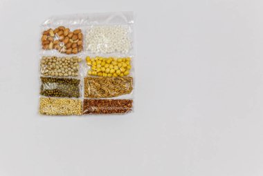 Mısır, Hardal, gram, Mung fasulye, zemin fındık, Kişniş küçük paketler beyaz bir arka plan üzerine yerleştirilir. Konuya seçici bir şekilde odaklanarak.