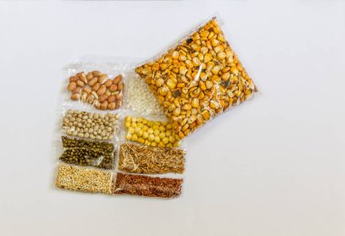 Mısır, Hardal, gram, Mung fasulye, zemin fındık, Kişniş küçük paketler beyaz bir arka plan üzerine yerleştirilir. Konuya seçici bir şekilde odaklanarak.