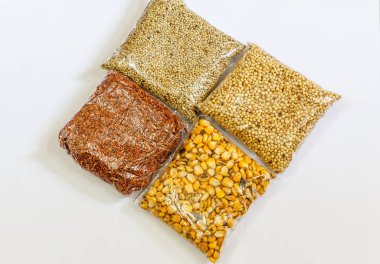 Mısır, Hardal, gram, Mung fasulye, zemin fındık, Kişniş küçük paketler beyaz bir arka plan üzerine yerleştirilir. Konuya seçici bir şekilde odaklanarak.