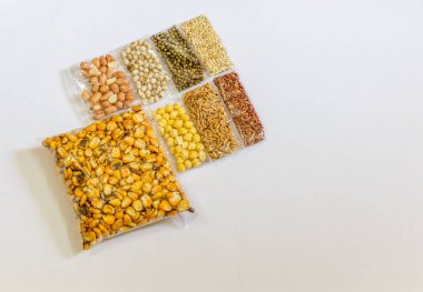 Mısır, Hardal, gram, Mung fasulye, zemin fındık, Kişniş küçük paketler beyaz bir arka plan üzerine yerleştirilir. Konuya seçici bir şekilde odaklanarak.