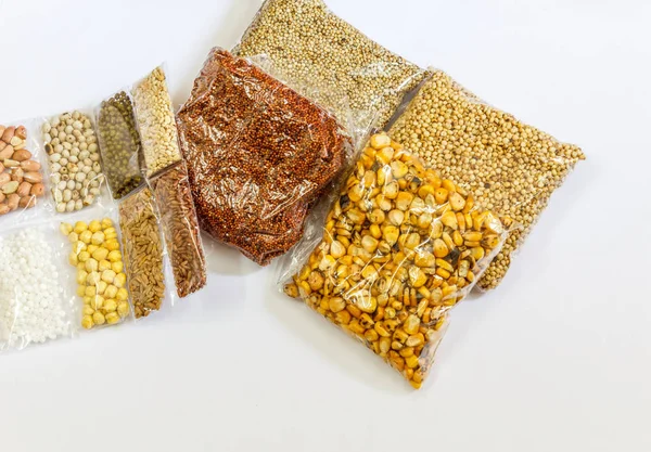 Mısır, Hardal, gram, Mung fasulye, zemin fındık, Kişniş küçük paketler beyaz bir arka plan üzerine yerleştirilir. Konuya seçici bir şekilde odaklanarak.