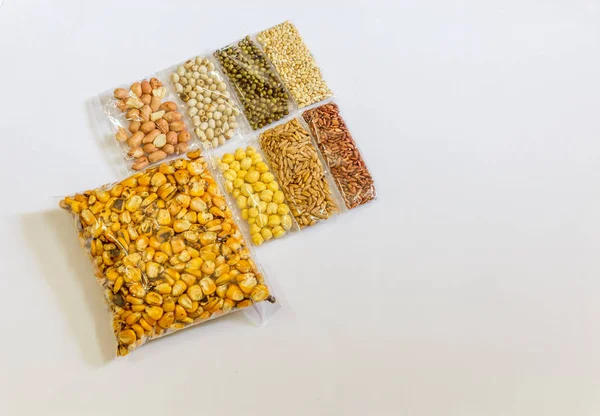 Mısır, Hardal, gram, Mung fasulye, zemin fındık, Kişniş küçük paketler beyaz bir arka plan üzerine yerleştirilir. Konuya seçici bir şekilde odaklanarak.