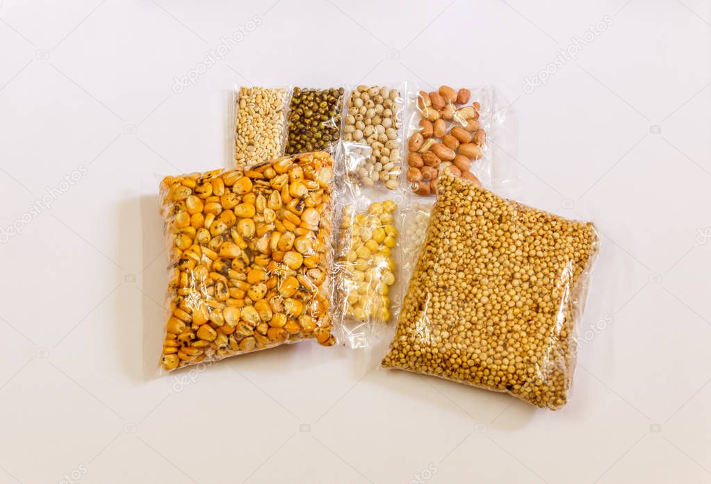 Smaller packets of Corn, Mustard, grams, Mung bean, ground nuts, Coriander placed on a white background. With selective focus on the subject.