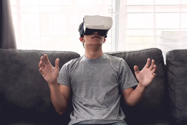 Un hombre alegre sentado en el sofá y el uso de la realidad virtual 3D g — Foto de Stock
