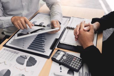 ofis konseptinde birlikte çalışan genç işadamları, toplantı ofisindeki piyasadaki durumu veya hisse senedi verim grafiğini tartışmak için touchpad dijital tablet kullanan genç işadamları